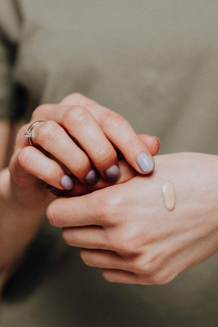 Fotografia de mãos com um pingo de base aplicada, utilizada para ilustrar artigo sobre base mary kay cores.