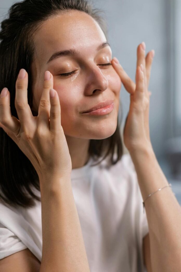 Fotografia de mulher aplicando creme nos olhos para ilustrar artigo sobre creme para área dos olhos.