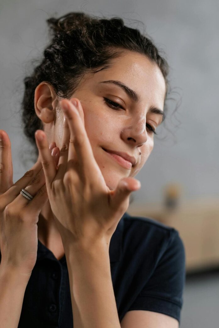 Fotografia de mulher tocando a pele, utilizada para ilustrar artigo sobre o primer Mary Kay.